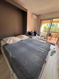 ル・ラヴァンドゥーにあるAPPARTEMENT ET SA JOLIE TERRASSE Le Lavandou Saint Clair, a deux pas de la plage de St Clair, au calme, Studio tout équipé, clim, Wifi Fibre, TV connectée, lave linge, lave vaisselle, place de parking et plus, serviettes et draps fournisのリビングルームのある部屋にある大きなベッド