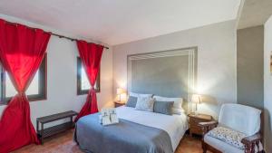 ein Schlafzimmer mit einem Bett und einem Stuhl und roten Vorhängen in der Unterkunft Cortijo Carrillo Antequera by Ruralidays in Antequera + 24 Fotos