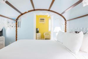 a bedroom with a white bed and a yellow wall at Deluxe King with Balcony - at James House with Parking! in Key West
