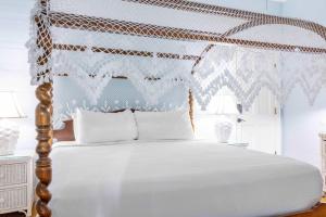 a bedroom with a white bed with a wooden headboard at Deluxe King with Balcony - at James House with Parking! in Key West