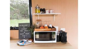 a microwave oven with a cutting board on top of it at Gumnut by Tiny Away in Kangaroo Valley +16 photos