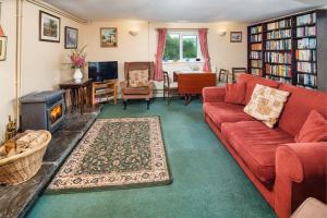 a living room with a red couch and a fireplace at Lower Cottage Newcastle Emlyn in Cwm-pengraig