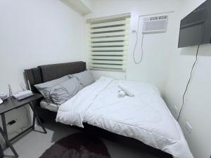 Cette chambre comprend un lit blanc, un bureau et une fenêtre. dans l'établissement Urban Deca Towers Cubao, à Manille