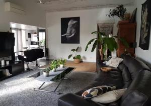 un salon avec un canapé en cuir noir et des plantes dans l'établissement Tropical Spirit House, à Marignane