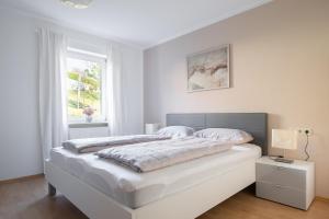 Un dormitorio blanco con una cama grande y una ventana. en Ferienwohnung Ella, en Meersburg