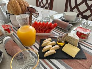 ein Tisch mit Käse und einem Teller mit Essen und Orangensaft in der Unterkunft Tia Vahine in Ivato