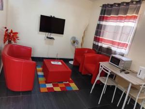 a living room with red chairs and a tv at Appartement Beau Séjour in Dakar