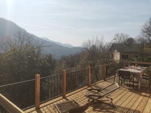 une terrasse en bois avec une table et des chaises sur un balcon dans l'établissement Gite Les Grillons, à Belvédère 11 autres photos