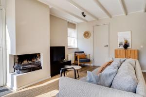 a living room with a couch and a fireplace at Kiekendief I Gerenoveerd Huisje in Scandinavische Stijl in Zwiggelte +34 photos