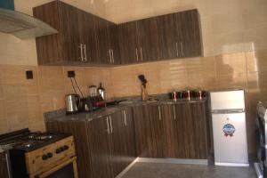 a kitchen with wooden cabinets and a refrigerator at The Vistana 4Bedroom Pearly Gate Estate Ikota VGC Lekki in Igboshere