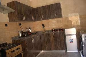 a kitchen with wooden cabinets and a white refrigerator at The Vistana 4Bedroom Pearly Gate Estate Ikota VGC Lekki in Igboshere