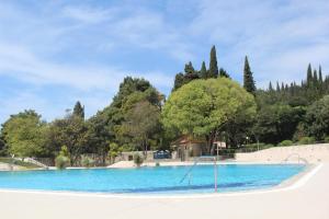 Una gran piscina azul con árboles al fondo. en Apartments Nika Mlini, en Mlini