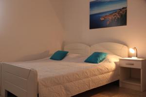 1 dormitorio con 1 cama blanca y 2 almohadas azules en Apartments Nika Mlini, en Mlini 84 fotos más