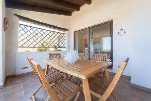 un tavolo e delle sedie di legno in una stanza di -Vista Mare e Piscina- Dimora di alta classe per 6 a Liscia di Vacca