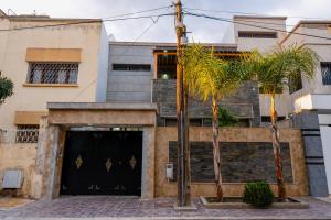 a building with a black door and two palm trees at Riad Les Champs De Fès in Fez