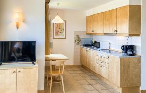 cocina con armarios de madera, mesa y TV en Nice Home In Hokjönköpingskillingaryd, en Svenstorp