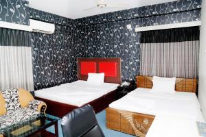 Una pequeña habitación con dos camas y una silla. en Hotel Luxury Inn, en Dhaka