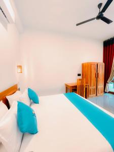 a bedroom with a large white bed with blue pillows at Peak Bay Resort in Arugam Bay +16 photos