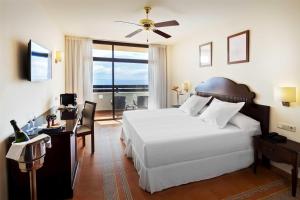 a bedroom with a large white bed and a balcony at Occidental Jandía Mar in Morro del Jable
