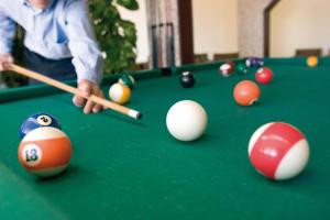 a man playing billiard with cue and balls on a pool table at Occidental Jandía Mar in Morro del Jable