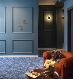 a living room with a orange chair and a door at The Oscar Olympic Hotel in Thessaloniki