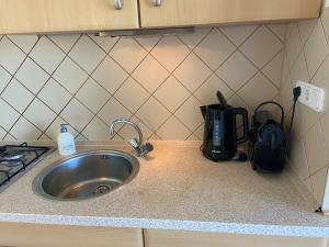 a kitchen counter with a sink and a stove at Sfeervol en gezellig gelegen appartement op Texel in De Koog +14 photos