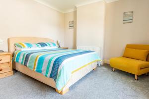 a bedroom with a bed and a yellow chair at Dog Friendly, Cosy Coastal Cottage, Sea Views in Portland
