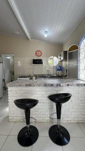 a kitchen with two black stools in front of a counter at Casa confortavel, bem equipada com Wi-Fi e garagem in Massaguassu