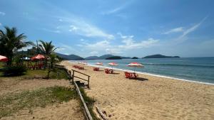 a beach with chairs and umbrellas and the ocean at Casa confortavel, bem equipada com Wi-Fi e garagem in Massaguassu