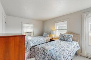 プロビンスタウンにあるBay Colony Retreatのベッド2台と椅子、窓のある寝室