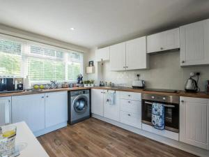 Una cocina con gabinetes blancos y lavadora. en Charming Beach Chalet with Balcony & Sea Views, en Pembrokeshire 15 fotos más