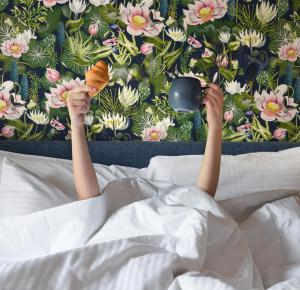 a person laying in bed holding a spoon and a mirror at The Oscar Olympic Hotel in Thessaloniki
