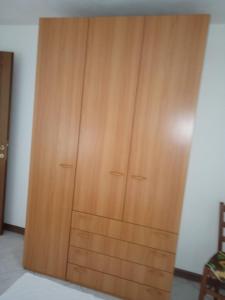 a wooden cabinet in a room with a chair at Lungomare 2 in Porto Alabe