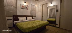 a bedroom with a bed with a green blanket at Mrudugandha Guest House in Nevra
