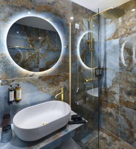 a bathroom with a sink and a glass shower at The Oscar Olympic Hotel in Thessaloniki