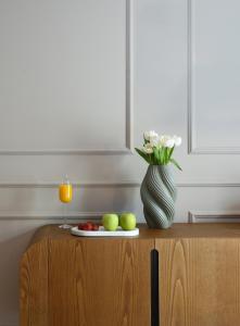a table with a vase and a plate of fruit and a glass of juice at The Oscar Olympic Hotel in Thessaloniki