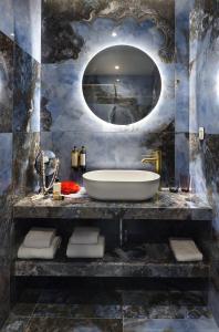 a bathroom with a tub and a round mirror at The Oscar Olympic Hotel in Thessaloniki