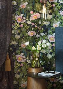 a wall with a floral wallpaper with a vase of flowers at The Oscar Olympic Hotel in Thessaloniki