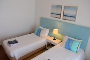 a small room with two beds and a lamp at Esplendor beiramar refúgio na Praia del Rey B9 in Amoreira +16 photos