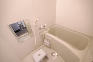 a white bathroom with a tub and a toilet at DAC Susukino in Sapporo