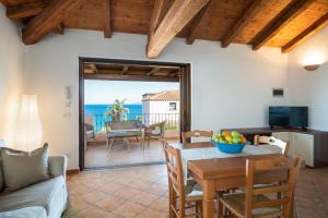 a living room with a table and a view of the ocean at Bellosguardo 3, 8 - Klodge in Olbia