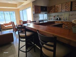 a kitchen with a large wooden bar with chairs at Casabamboo in Paraíso