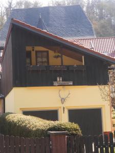 uma casa com um telhado preto e uma cerca em Ferienhaus Waterstrat em Stolberg i. Harz