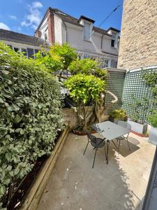 a patio with a table and chairs next to a hedge at Wisteria in Fontainebleau +10 photos