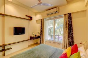 a bedroom with a large window and a tv at Coastal Living -1RK Apartment Goa in Arpora