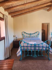a blue bed in a room with a wooden ceiling at El Hornero in Tilcara