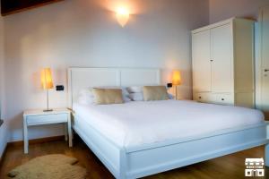 een slaapkamer met een groot wit bed en twee lampen bij PERLA 7 by Design Studio in Bellano +28 foto's