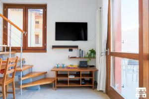 een woonkamer met een tafel en een tv aan de muur bij PERLA 7 by Design Studio in Bellano