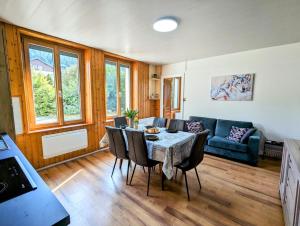 een woonkamer met een tafel, stoelen en een bank bij Appartement Chaleureux Gérardmer proche forêt in Gérardmer