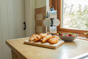 a bunch of croissants and a bowl of strawberries on a counter at Dog Friendly, Cosy Coastal Cottage, Sea Views in Portland +37 photos